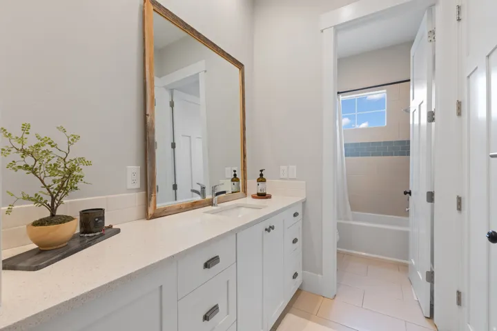 Bathroom featuring a white vanity with an undermount sink, a light-toned countertop, and a wood-framed mirror