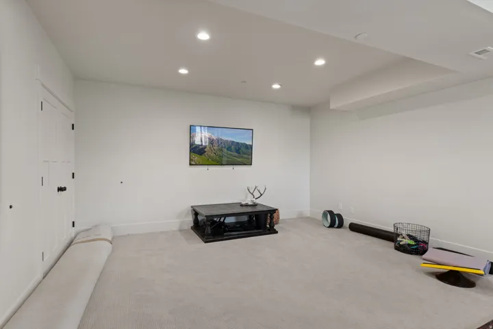 Spacious room featuring light-colored carpet, white walls, and recessed lighting