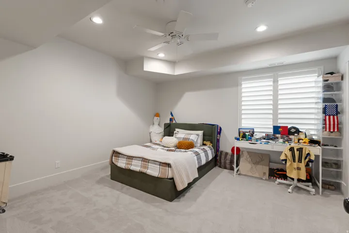 Carpeted room featuring a ceiling fan with integrated lighting, recessed lighting, white walls, and a window with white plantation shutters