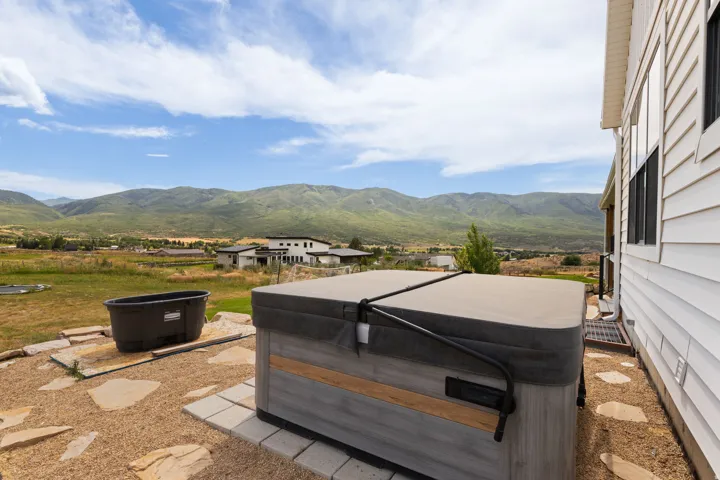 Exterior hot tub with a neutral cover and wood-finish paneling, situated on a flagstone and gravel patio