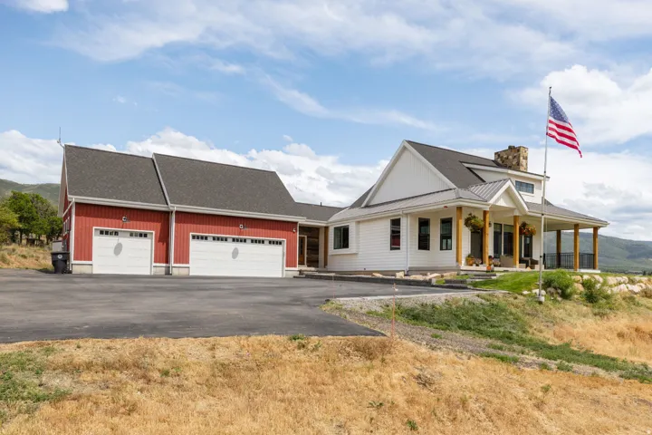 Modern farmhouse-style residence featuring white siding and a covered porch with natural wood columns