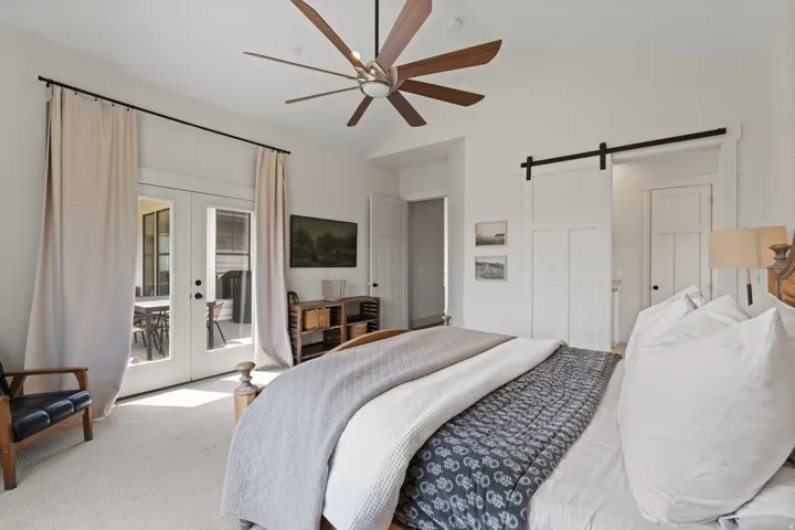 Vaulted ceiling bedroom with a large ceiling fan and wood-finish blades