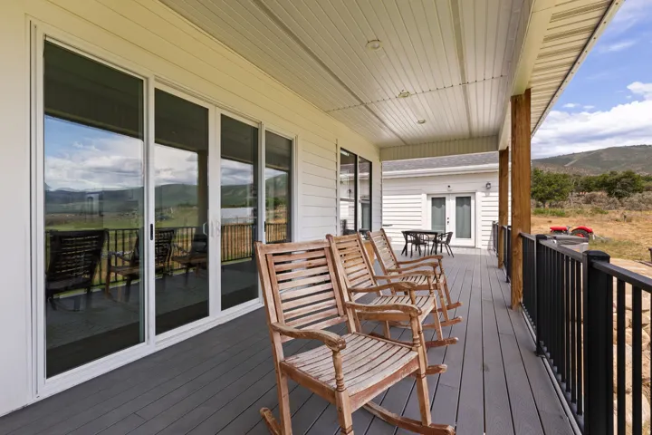 Expansive covered patio featuring grey composite decking, white siding, and wood structural columns
