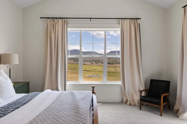 Vaulted ceiling room featuring a large multi-pane window, neutral walls, and plush carpet flooring