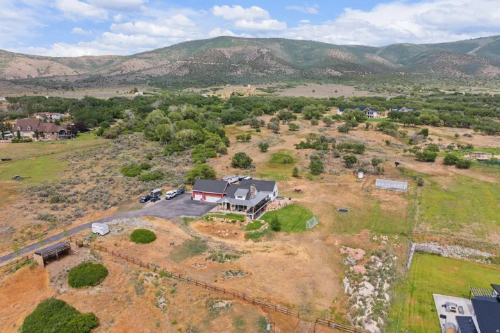 Expansive property featuring a multi-level residence with a red garage door, a paved driveway, and multiple outbuildings