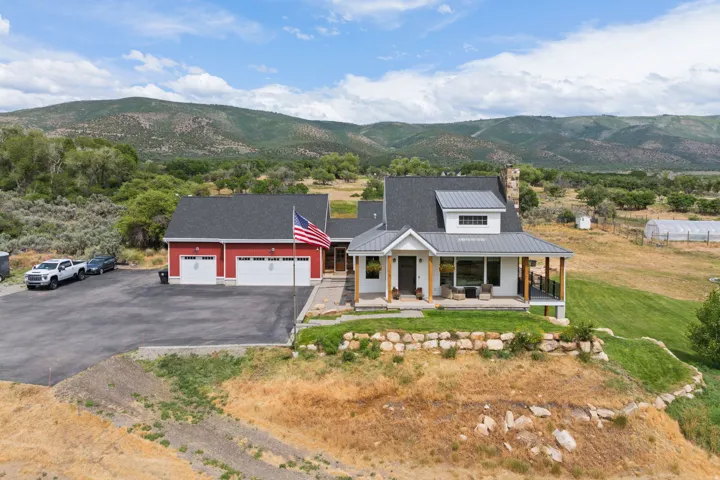 Modern farmhouse-style residence featuring a prominent covered porch with wood columns and a stone chimney