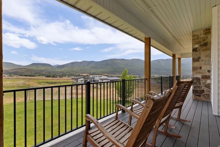 Expansive covered porch featuring wood support beams, a composite decking surface, and a black metal railing