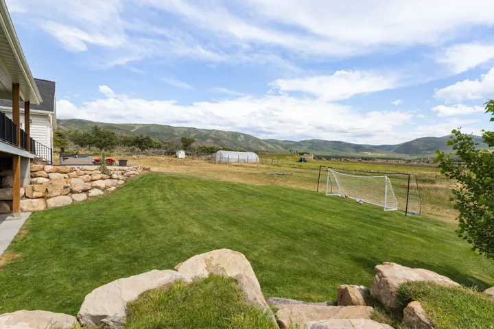 Expansive green lawn with a natural rock retaining wall