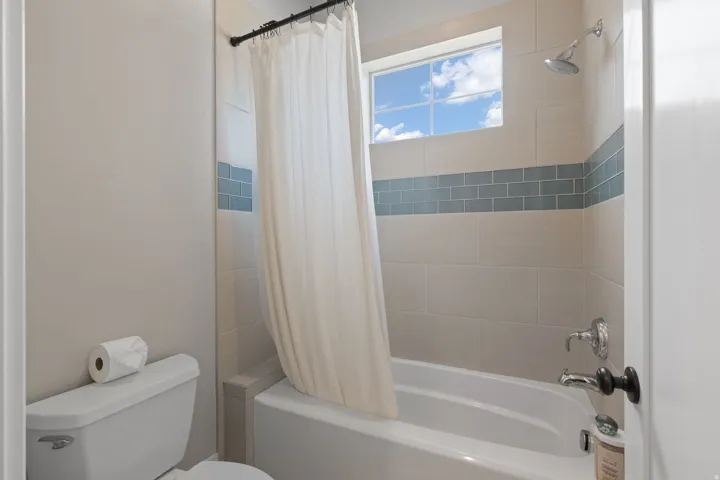 Bathroom featuring a white tub, chrome fixtures, and tiled walls with a decorative blue accent band