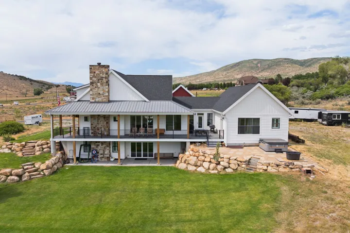 Two-story residence featuring white siding, a dark shingle roof, and a prominent stone-clad chimney