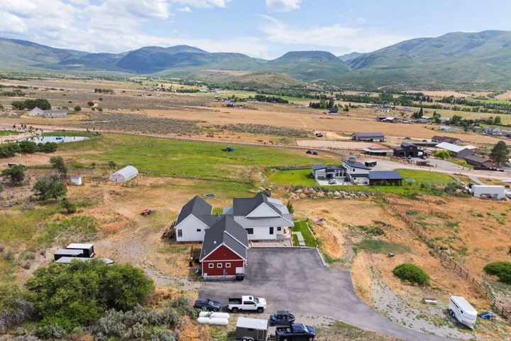 Expansive rural property featuring a main residence with a white exterior and dark roof, a red barn-style structure, a large paved driveway, and multiple outbuildings