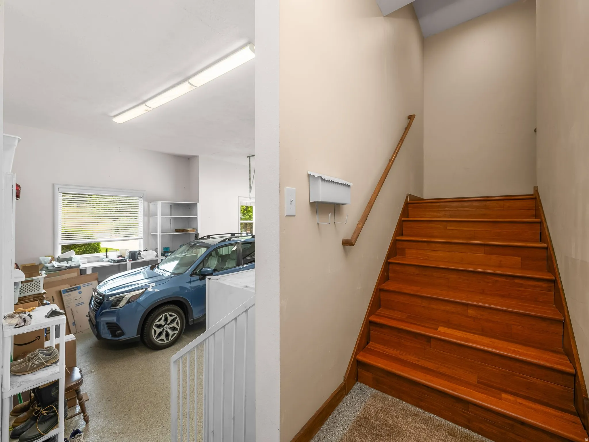 Wood-finish staircase with a coordinating wood handrail leading to ADU above garage.