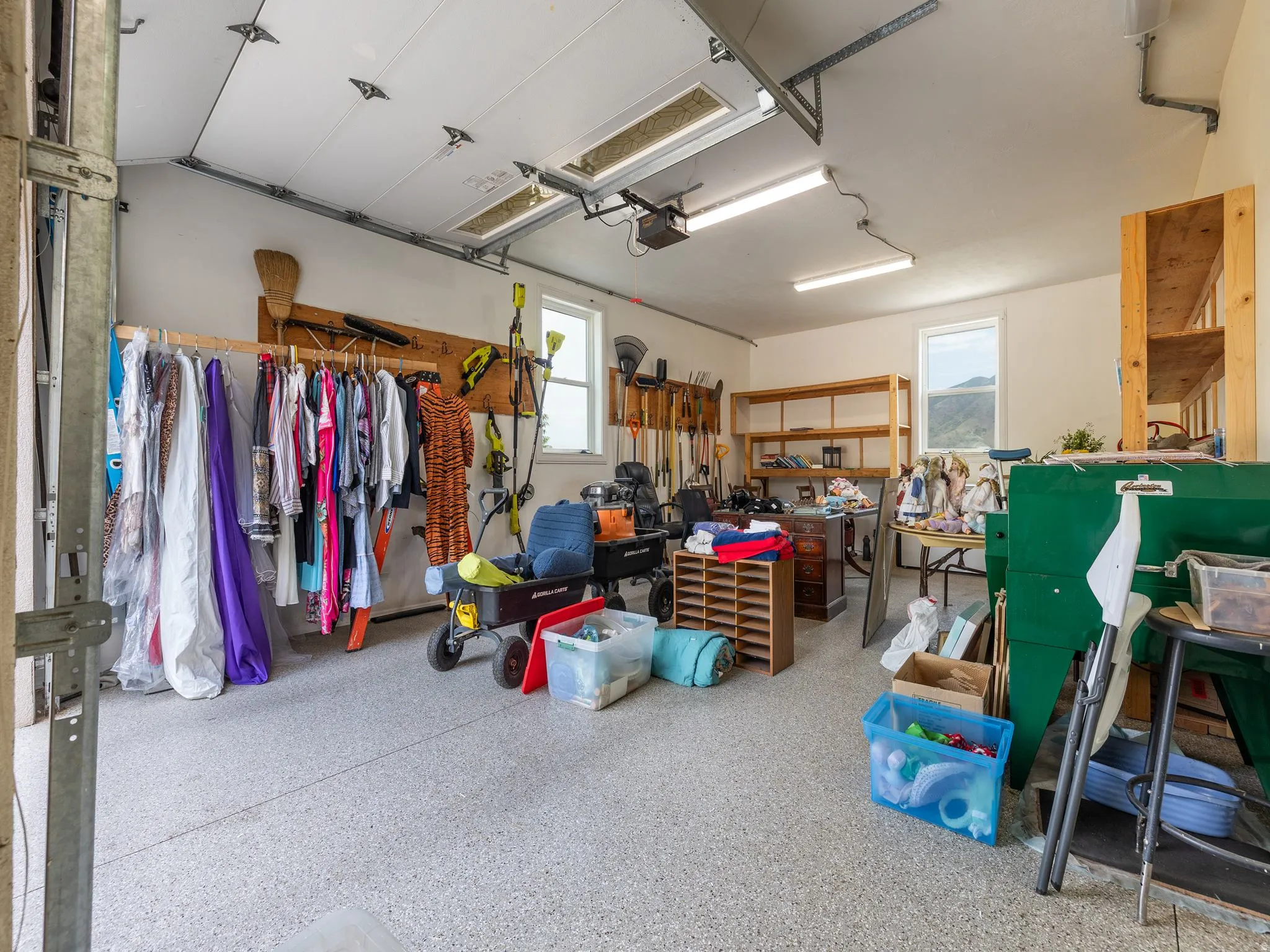 Garage interior featuring a speckled epoxy floor, overhead fluorescent lighting, and two windows providing natural light