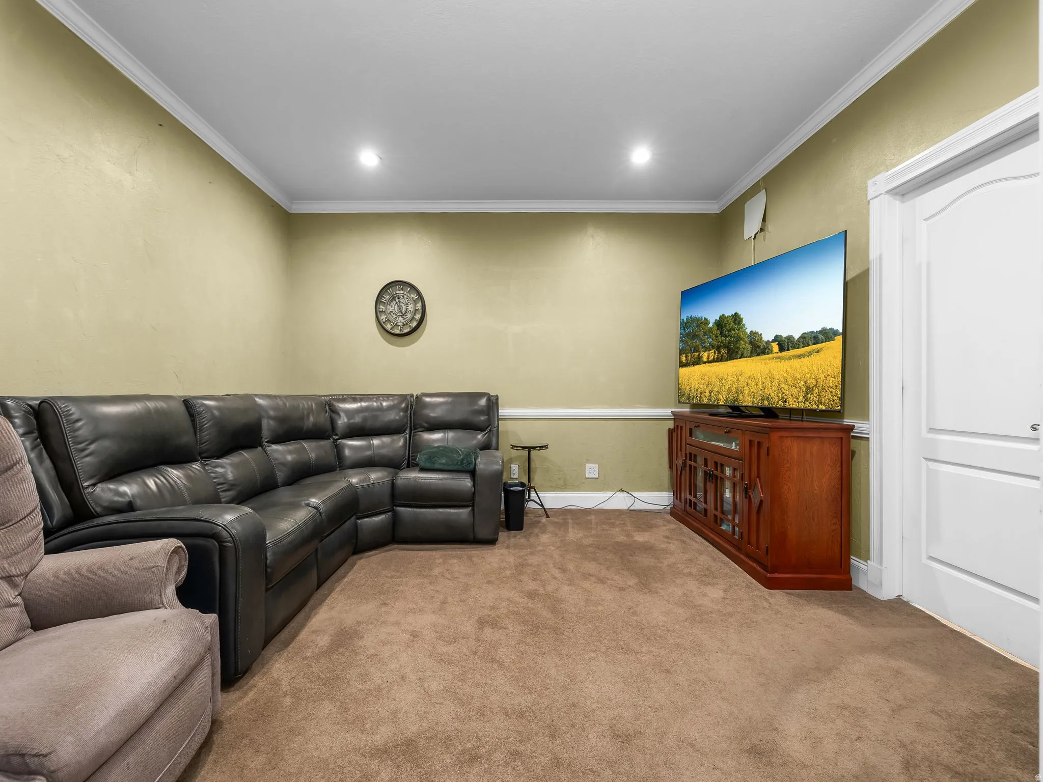 Carpeted living space featuring recessed lighting, crown molding, and a white interior door