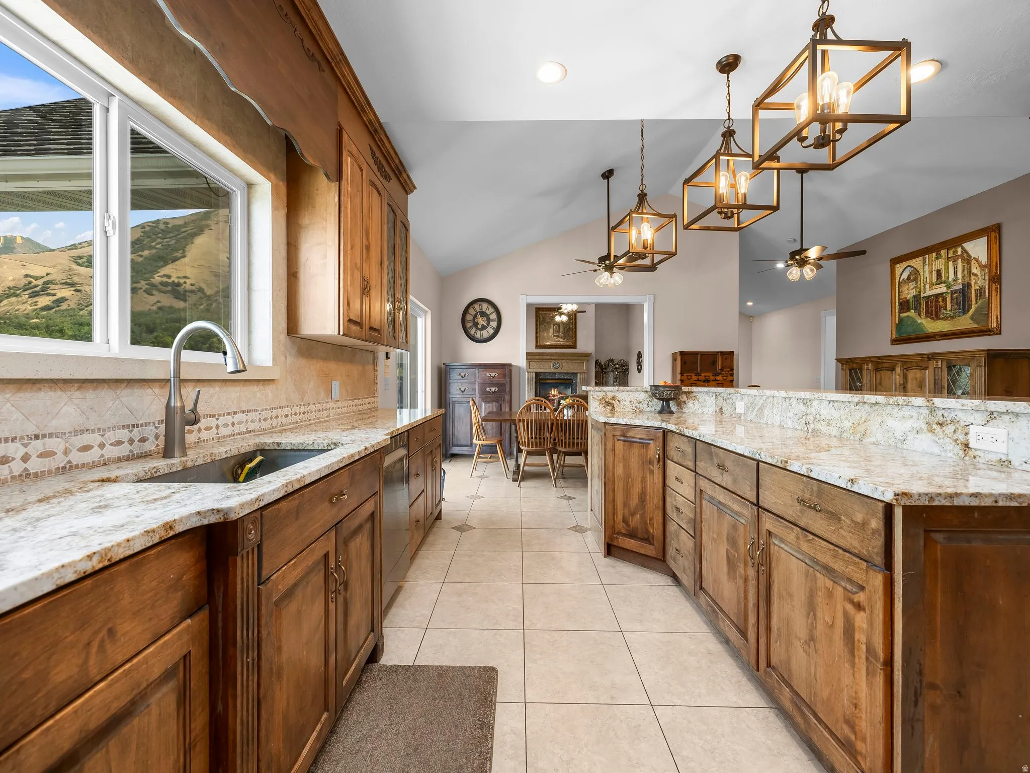 Kitchen featuring extensive wood cabinetry, light granite countertops, a tile backsplash, and a stainless steel sink with a gooseneck faucet