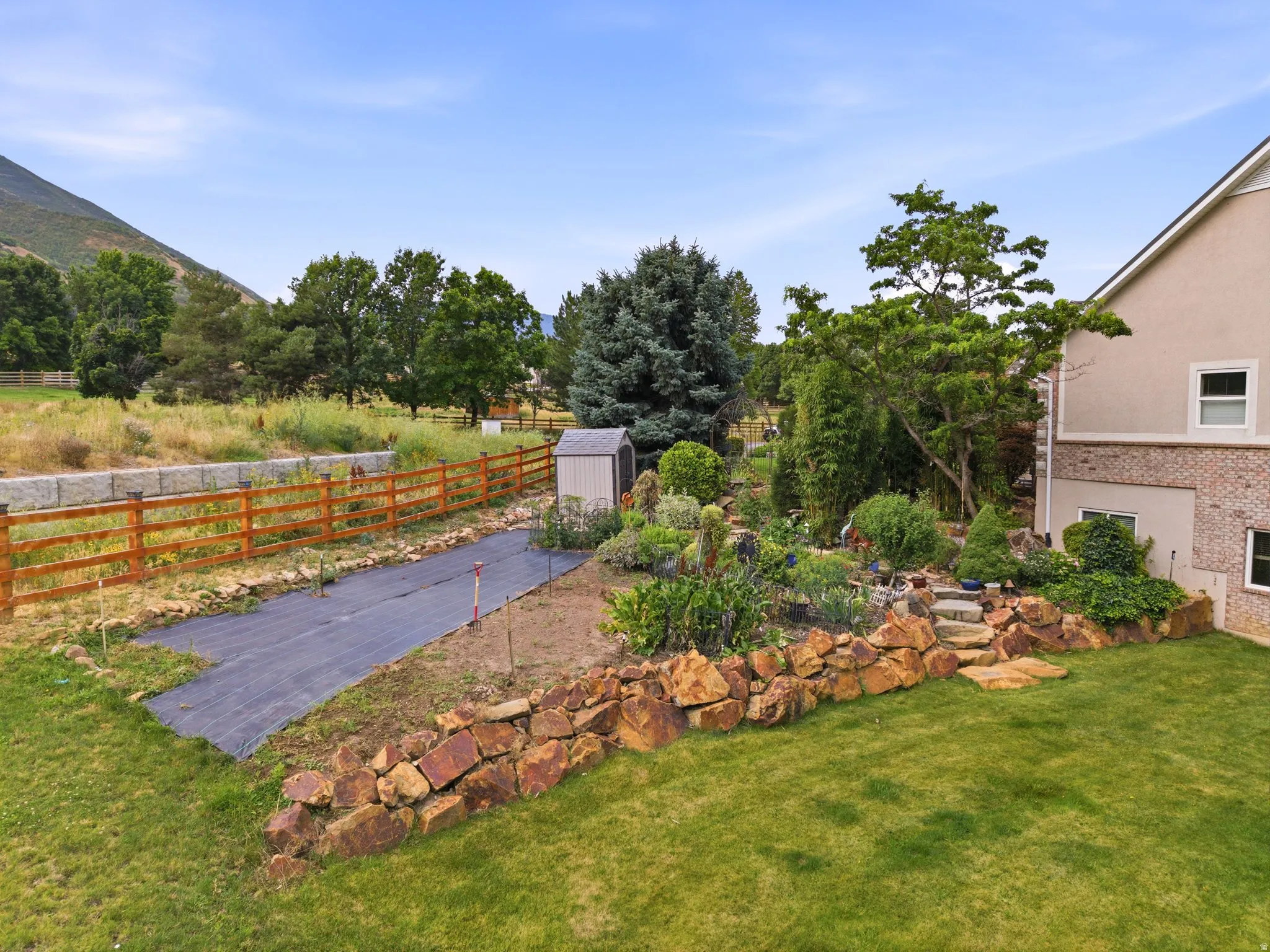 Expansive backyard featuring a manicured lawn, established landscaping, and a tiered rock garden