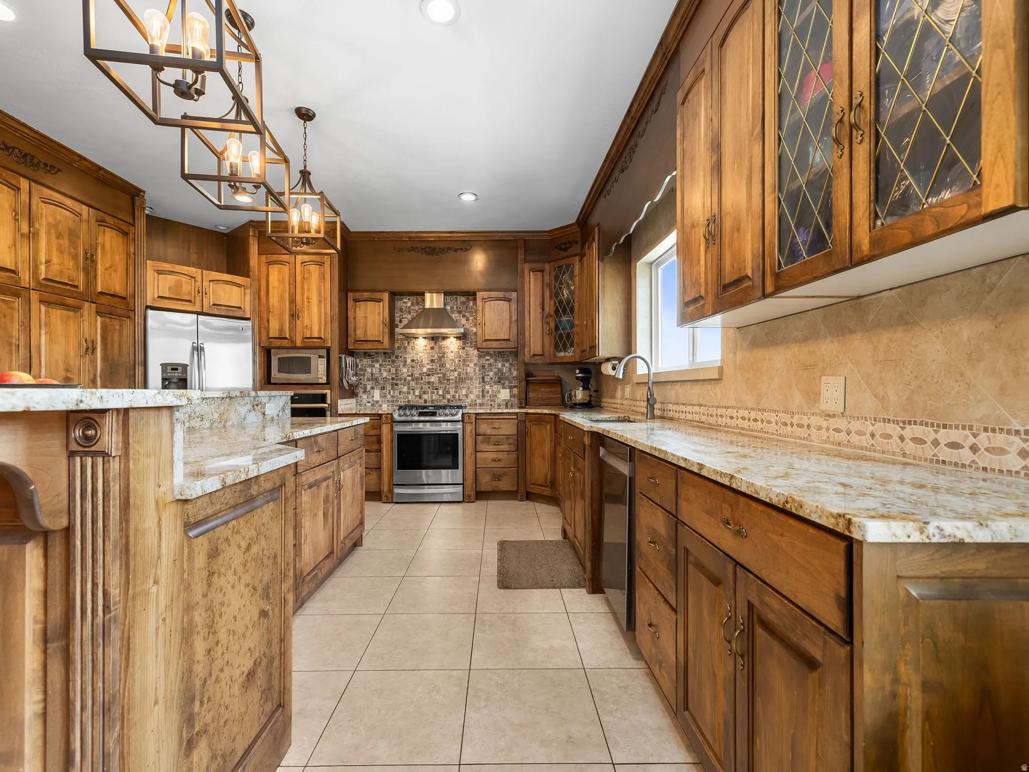 Spacious kitchen featuring extensive wood cabinetry, granite countertops, stainless steel appliances, a tiled backsplash, and recessed lighting