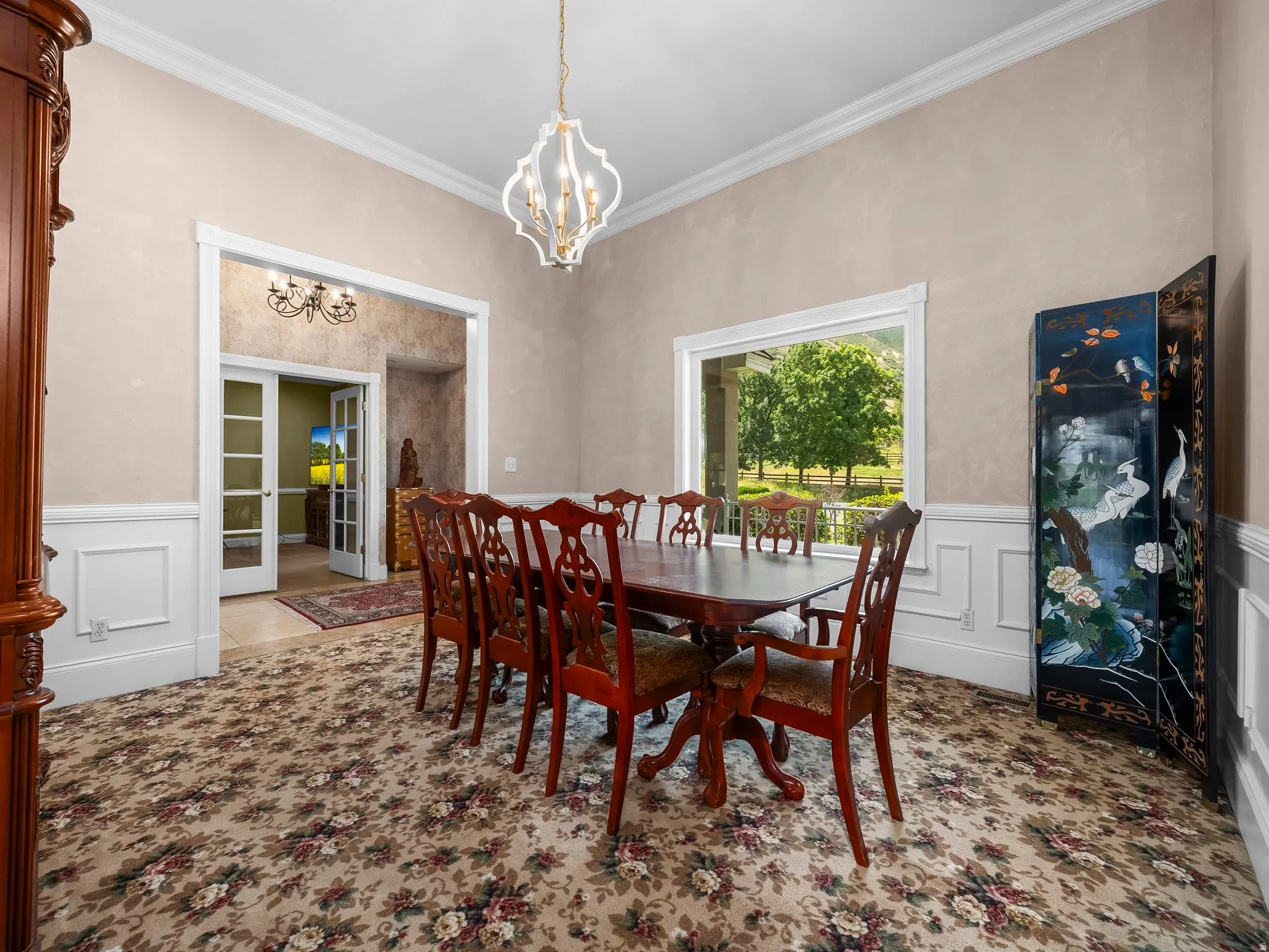 Dining area featuring a decorative chandelier, crown molding, and wainscoting