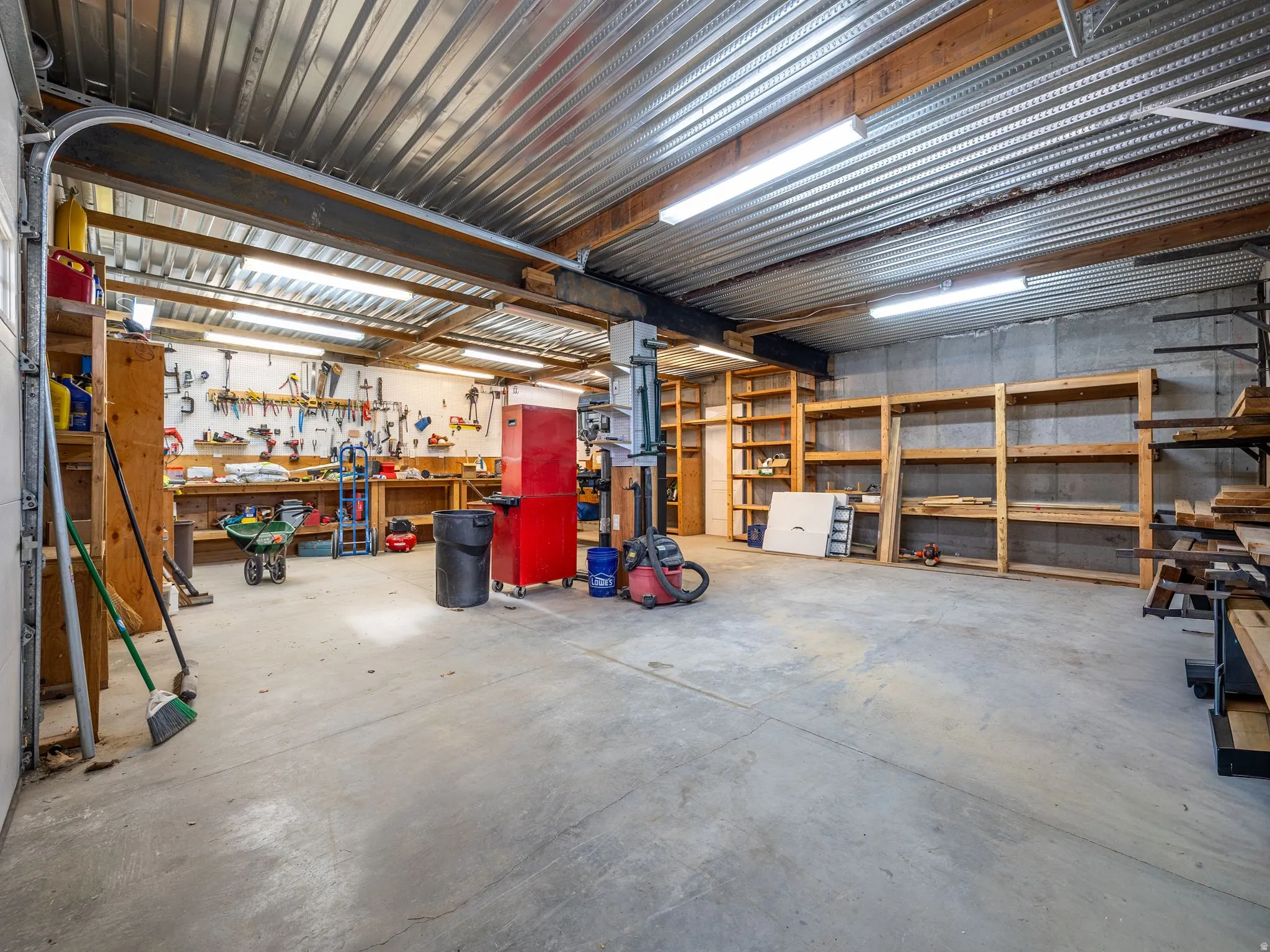 Garage space featuring a concrete floor, corrugated metal ceiling, and exposed support beams