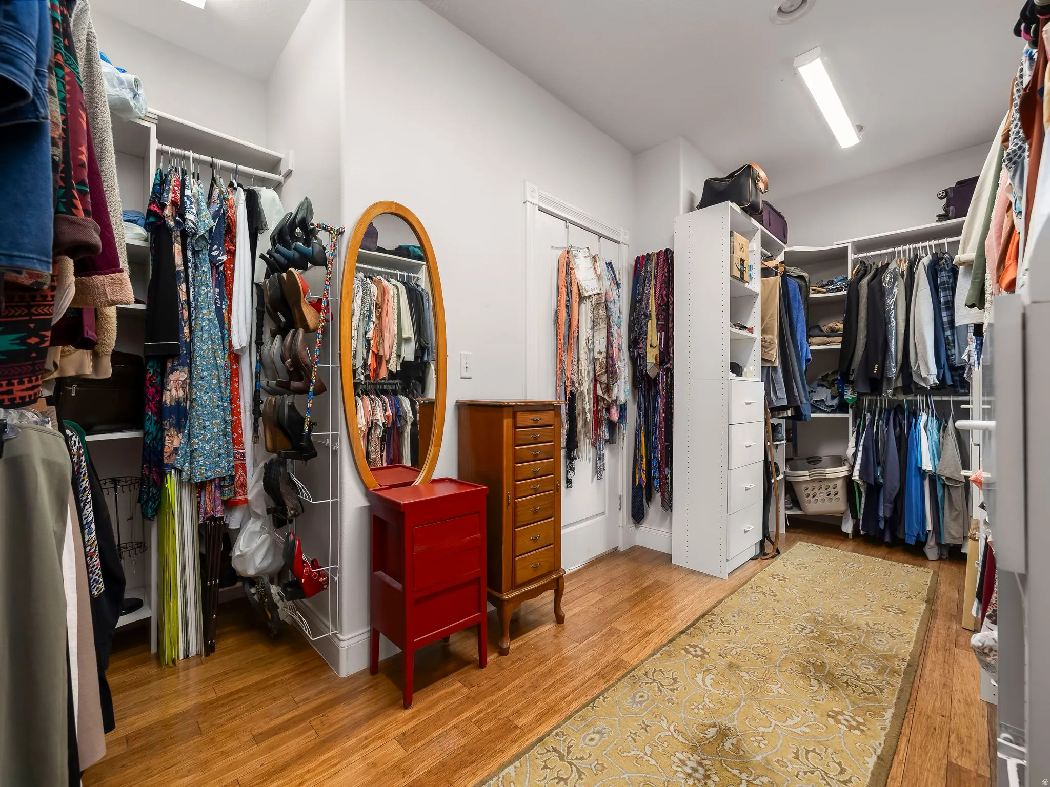 Spacious walk-in closet featuring extensive built-in shelving, hanging rods, and wood-finish flooring