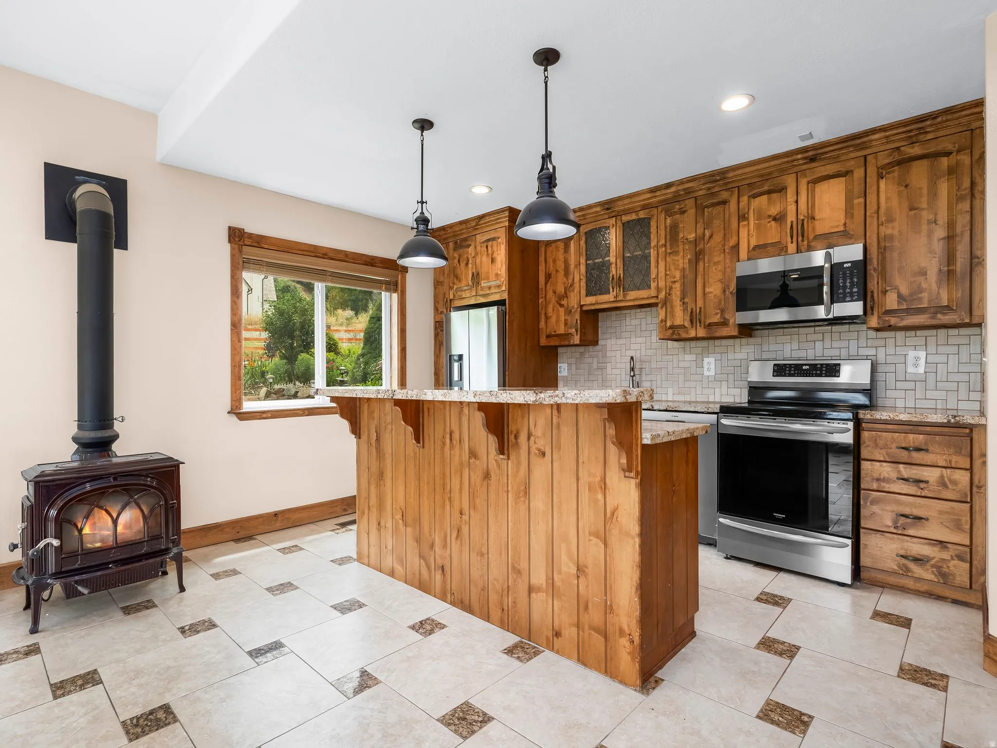 Basement Kitchen featuring knotty pine cabinetry, stainless steel appliances, and a mosaic tile backsplash