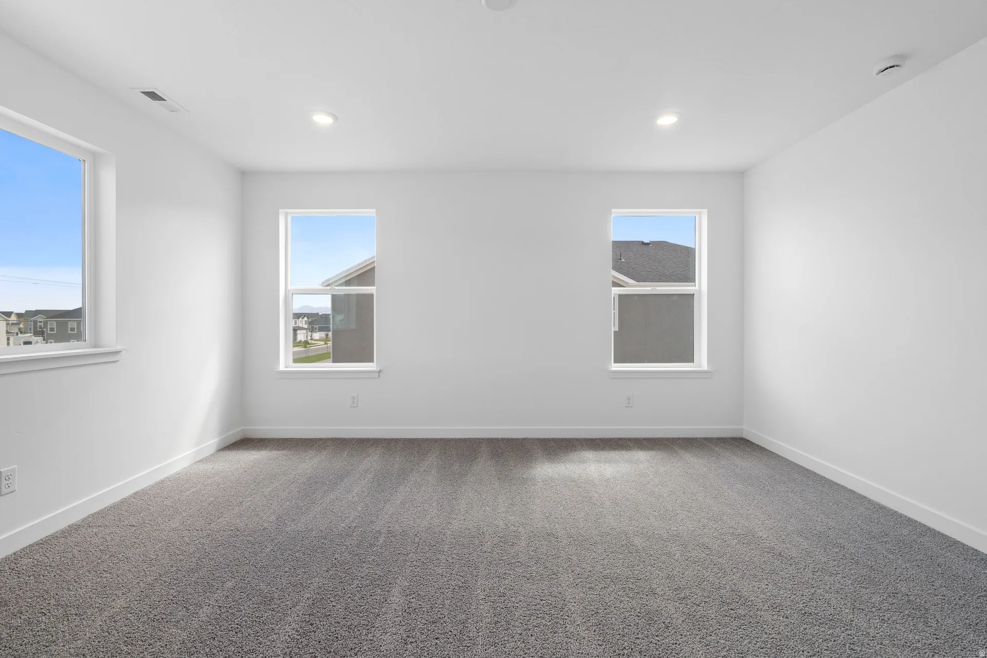 Spacious interior room featuring light gray carpet flooring and white painted walls