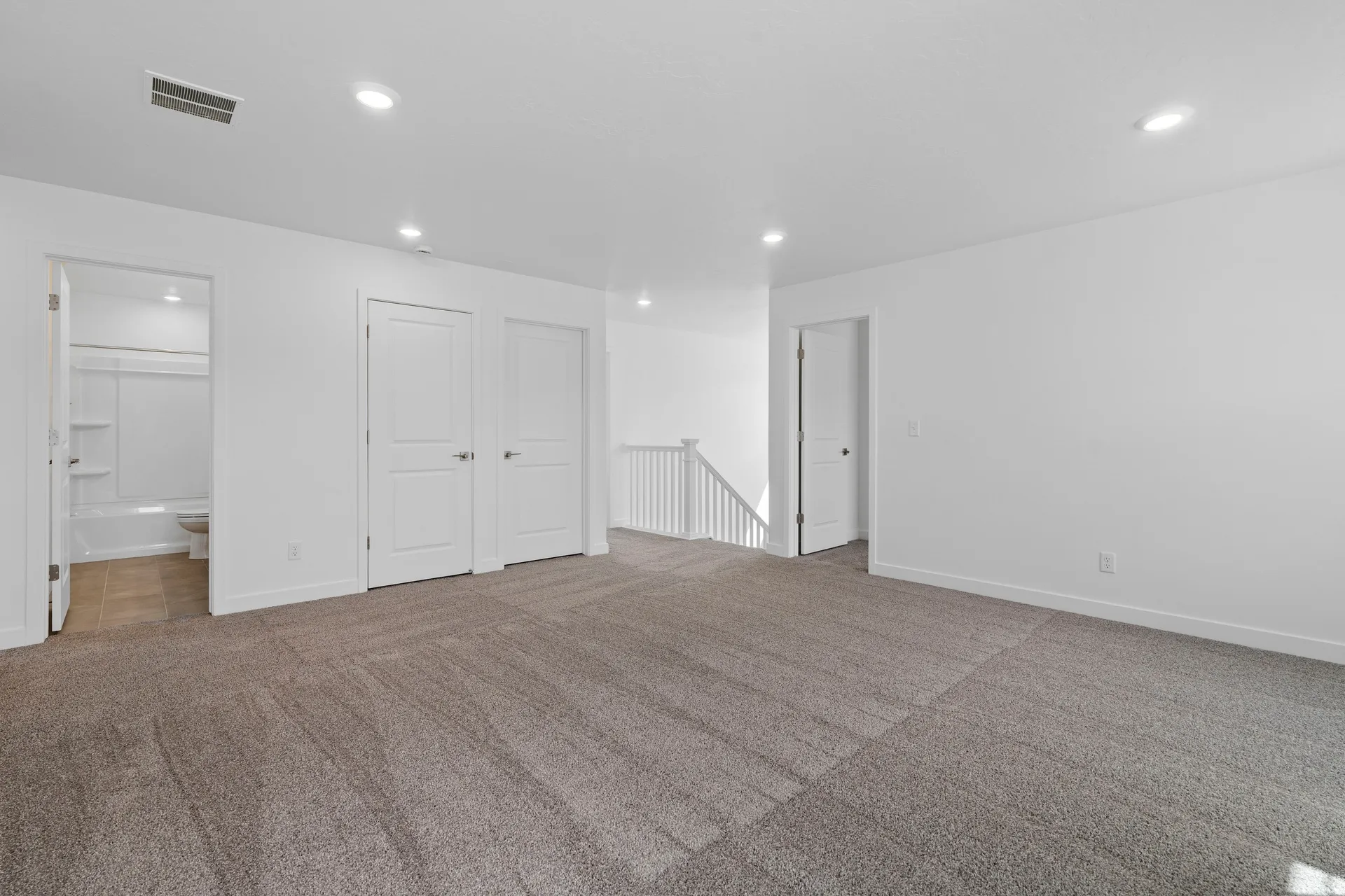 Spacious carpeted room featuring recessed lighting, white walls, and bright white trim