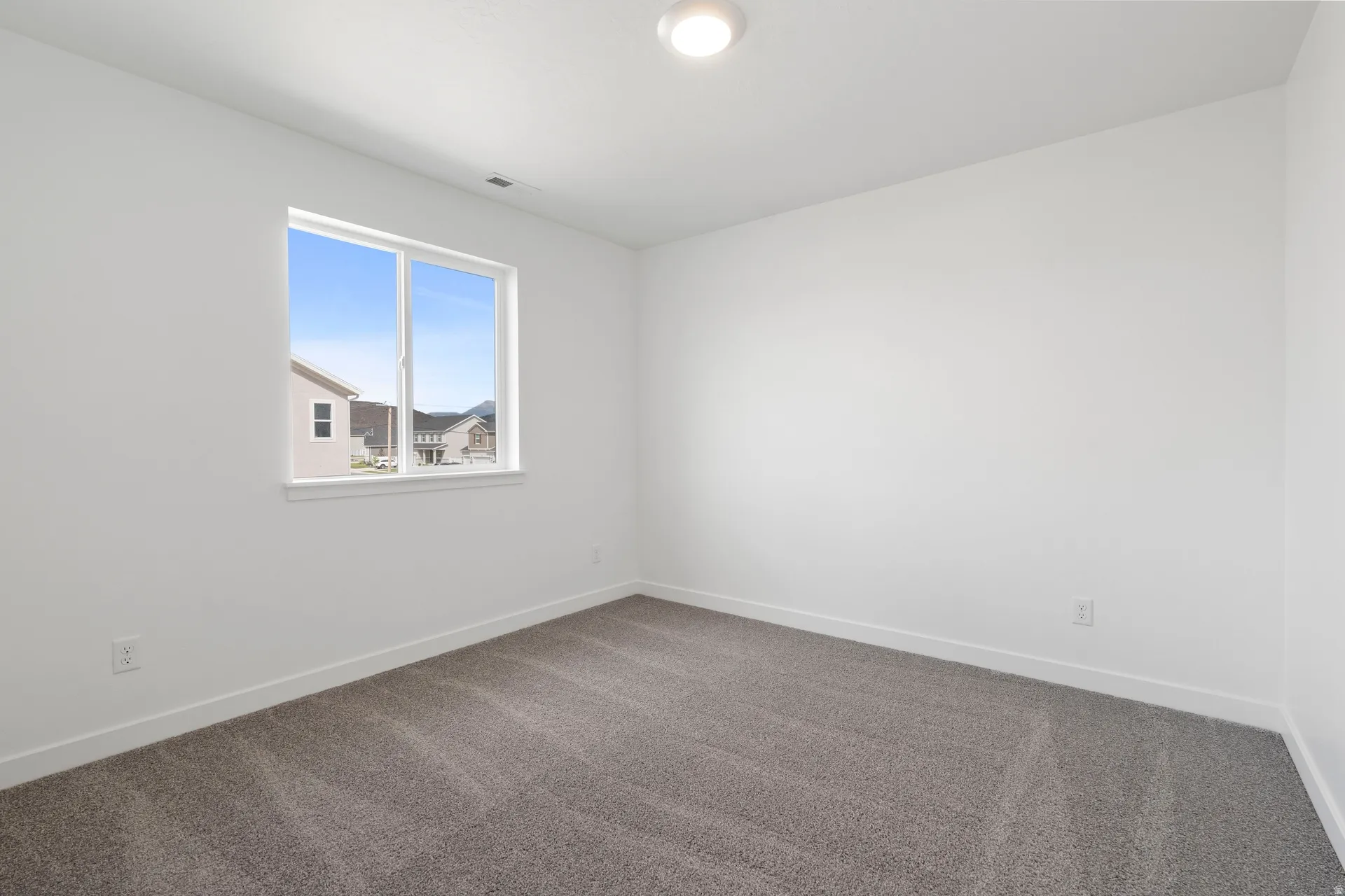 White walls with white trim, gray carpeting, and a double-pane window