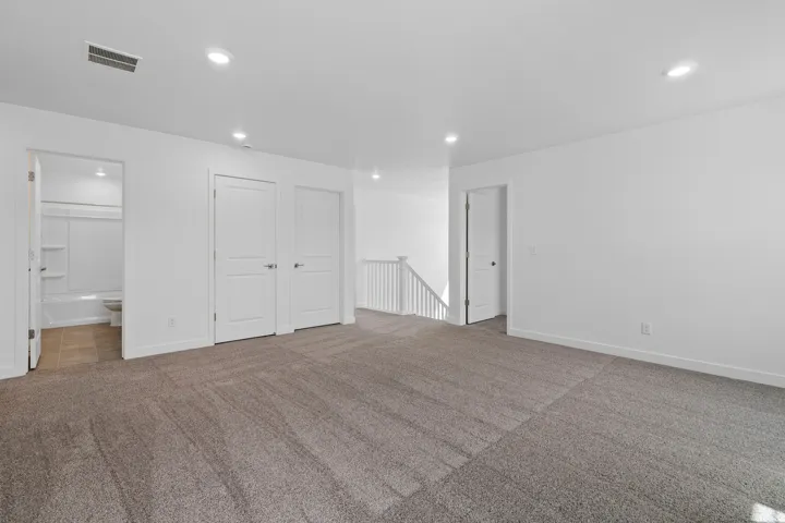Spacious carpeted room featuring recessed lighting, white walls, and bright white trim