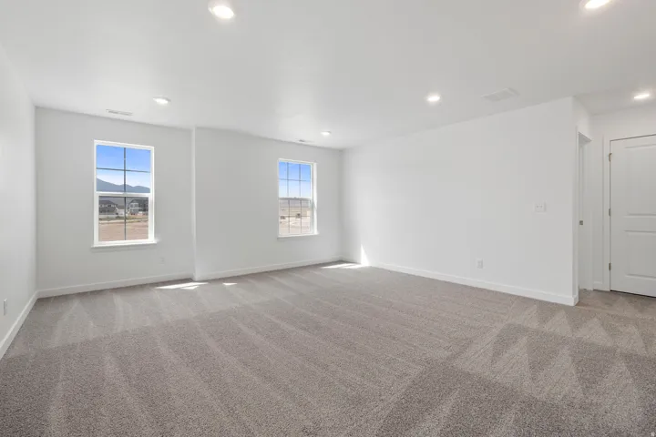 Spacious room featuring neutral carpeting, recessed ceiling lighting, and two windows
