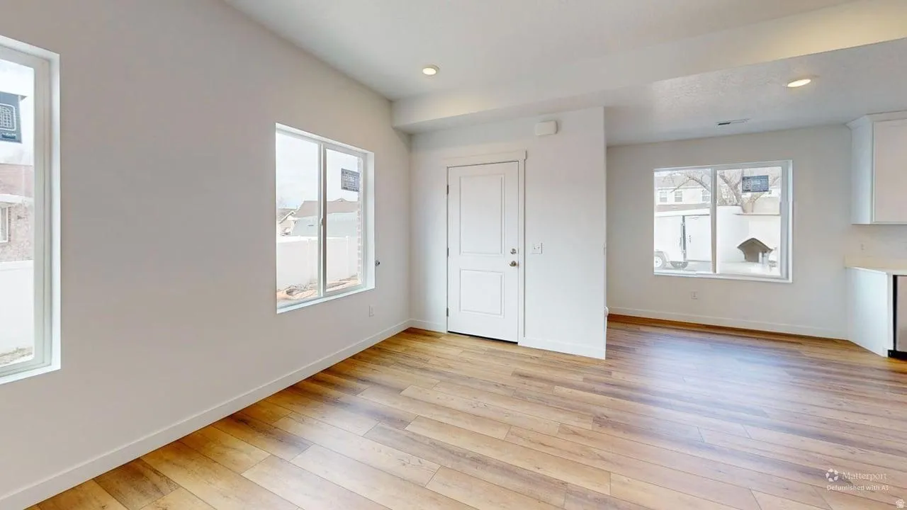 Expansive open-concept space featuring wood-finish flooring, recessed lighting, multiple windows, and a crisp white color palette