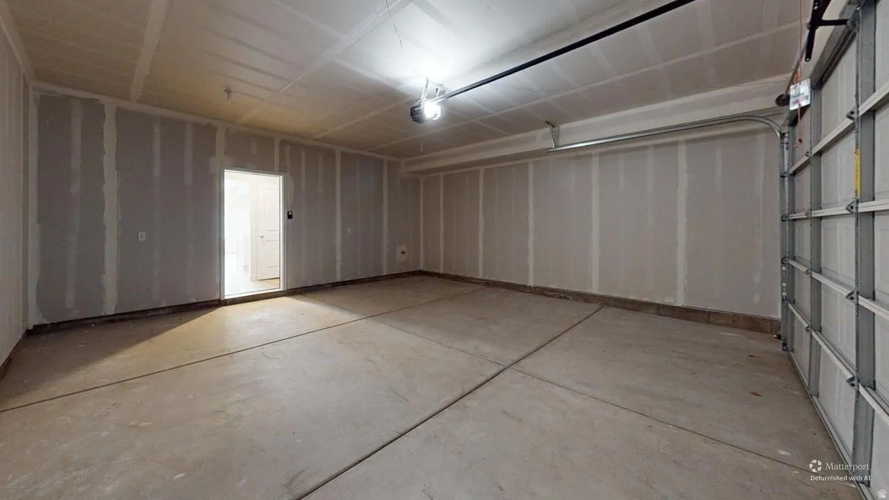 Spacious garage with concrete flooring, automatic garage door opener, and unfinished gypsum board walls