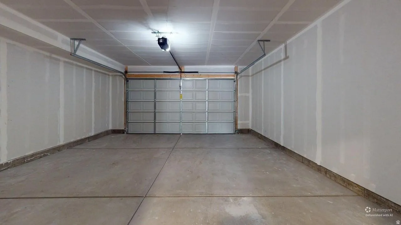 Spacious two-car garage featuring a sectional overhead door, concrete flooring, and an automatic garage door opener