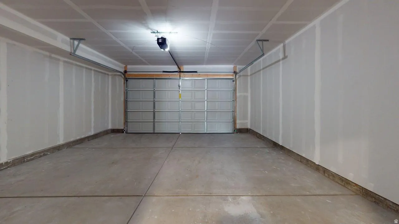 Spacious garage with a sectional garage door, concrete flooring, and an automatic garage door opener