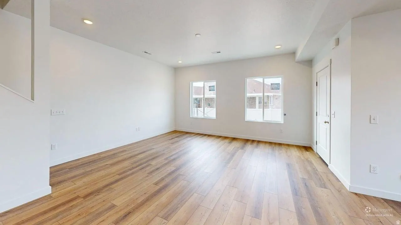Spacious interior featuring wood-finish flooring, white walls, recessed lighting, and bright windows