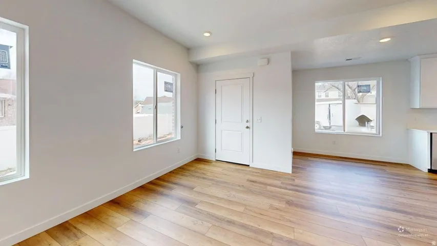 Expansive open-concept space featuring wood-finish flooring, recessed lighting, multiple windows, and a crisp white color palette