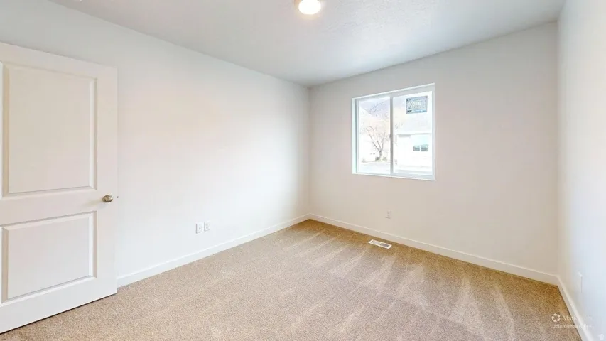 Neutral-toned room featuring a single window, recessed lighting, a paneled door, and light-colored carpeting