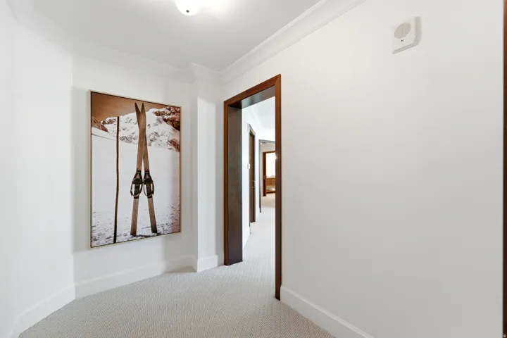 Hallway featuring textured carpet flooring and white crown molding