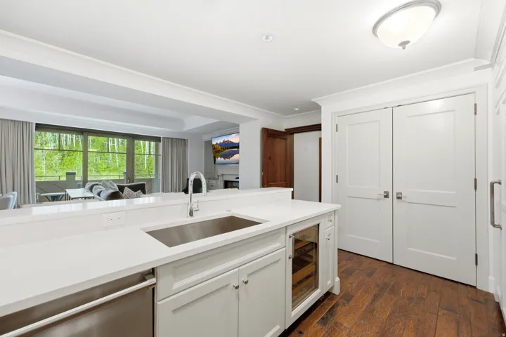 Kitchen island featuring a stainless steel sink, integrated dishwasher, and a built-in beverage cooler