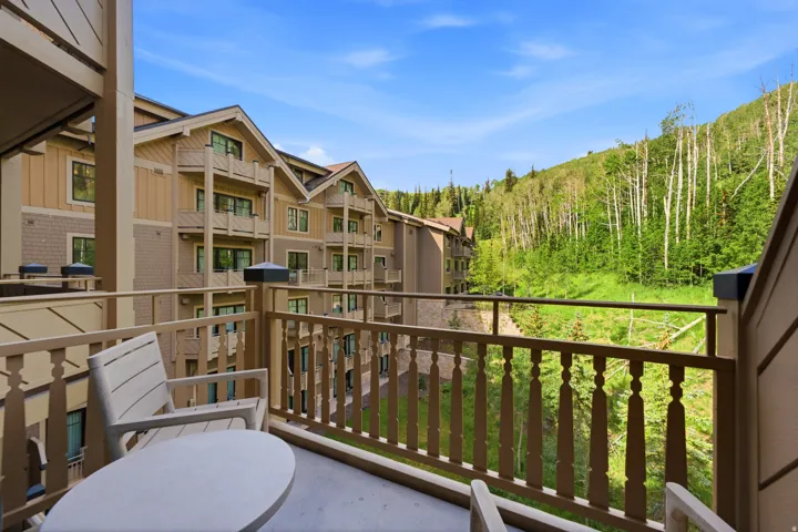 Private balcony with wood railing, offering expansive mountain scenery and mature trees