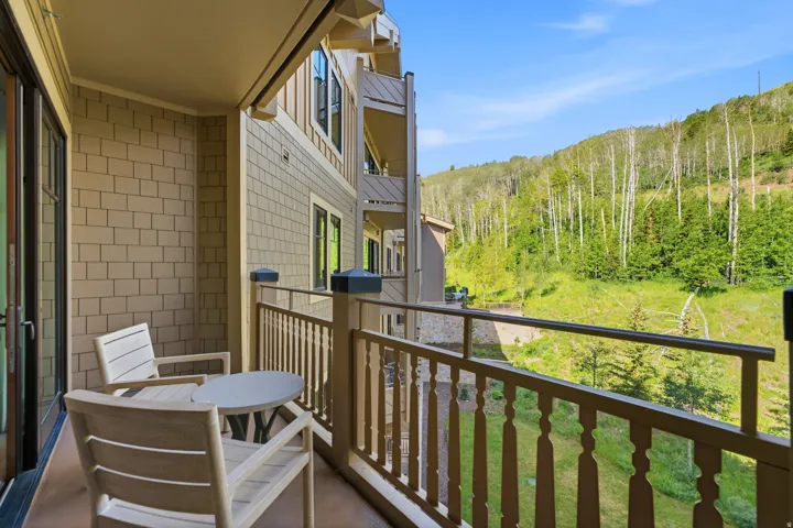 Private outdoor balcony featuring a painted wood railing, an exterior wall with horizontal siding, and a sliding glass door