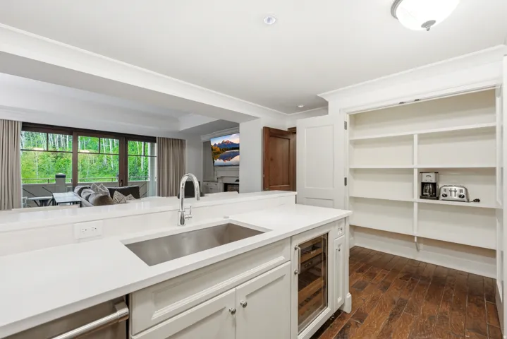 Kitchen featuring a stainless steel undermount sink, a built-in beverage refrigerator, white cabinetry, and quartz countertops
