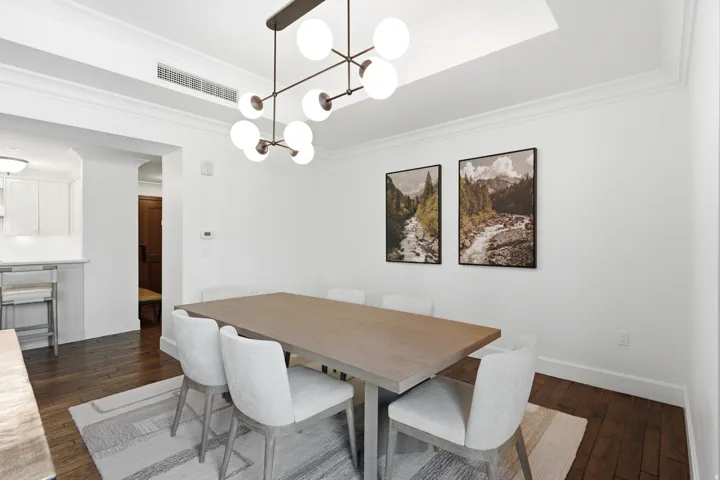 Dining area featuring dark wood-finish flooring, white crown molding, a contemporary multi-bulb chandelier, and a recessed ceiling panel