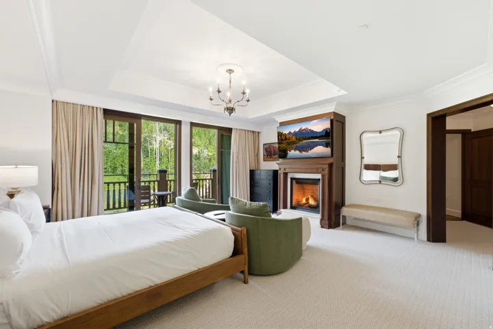 Spacious room featuring a tray ceiling with crown molding, a built-in fireplace with a wood surround, and direct access to an outdoor balcony