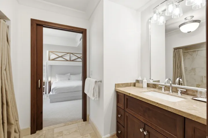 Bathroom vanity featuring a single basin, polished chrome faucet, and stone countertop
