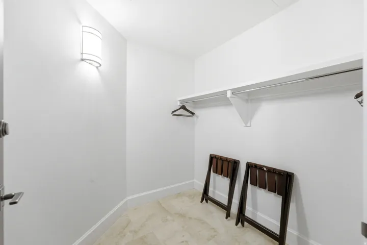 Recessed closet featuring a wall-mounted light fixture, upper shelving, and a metal hanging rod