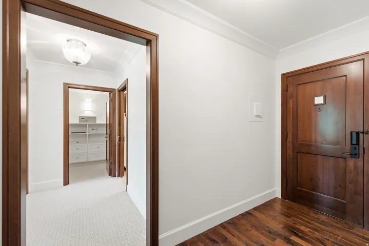 Entryway featuring dark wood-finish flooring, a paneled wood door with a digital lock, and crown molding