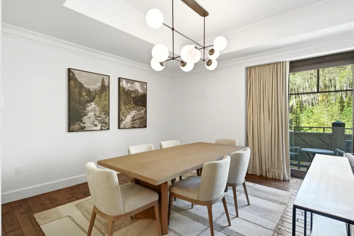 Dining area with wood-finish flooring, crown molding, and a modern globe chandelier