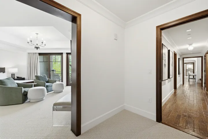 Hallway featuring wood-finish flooring, white walls, and dark wood trim