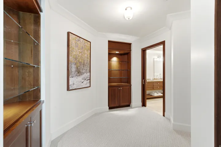 Hallway featuring light-toned carpeting and white walls with crown molding